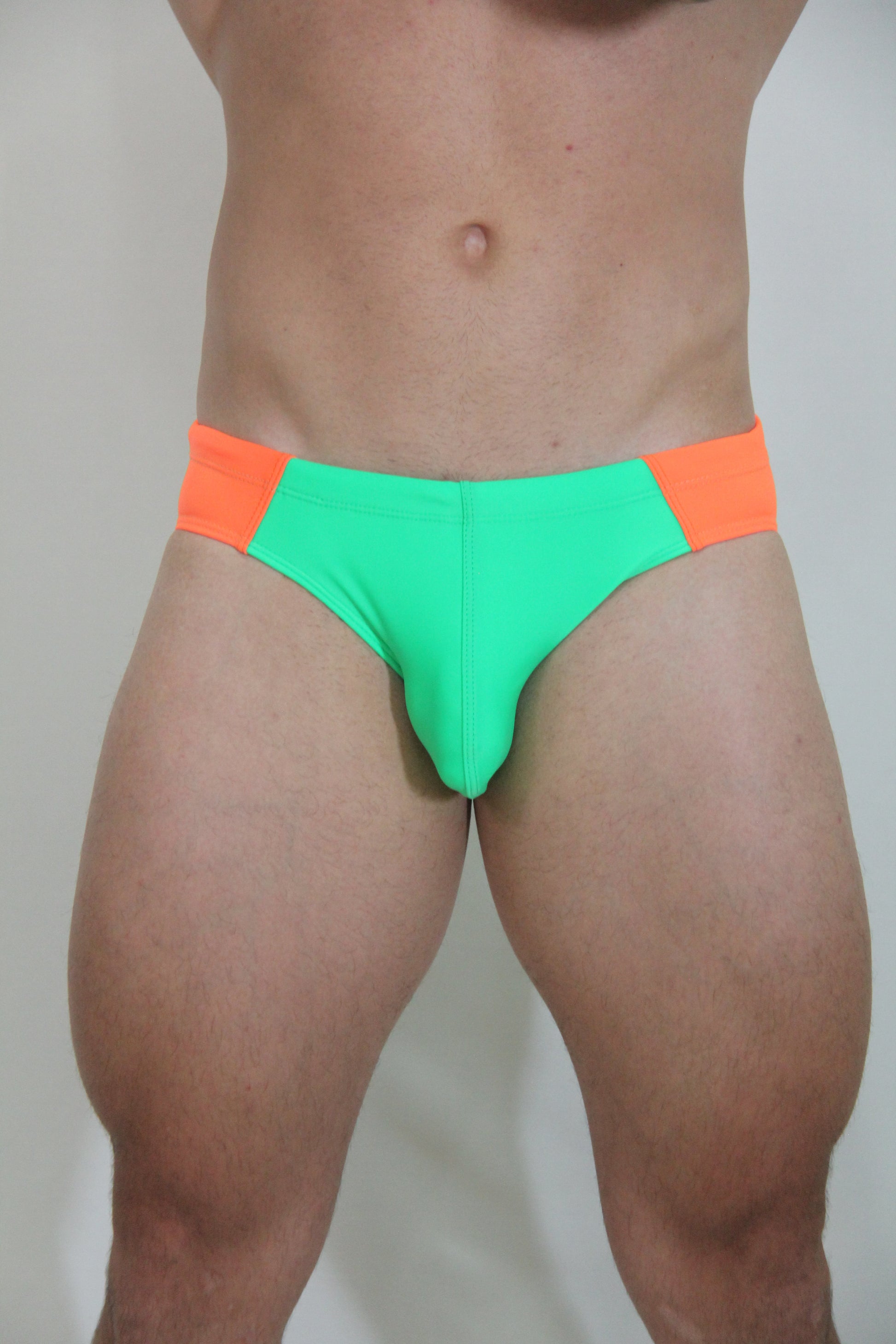 Neon curved swim brief in bright green and orange with a snug, form-fitting design for swimming and beachwear