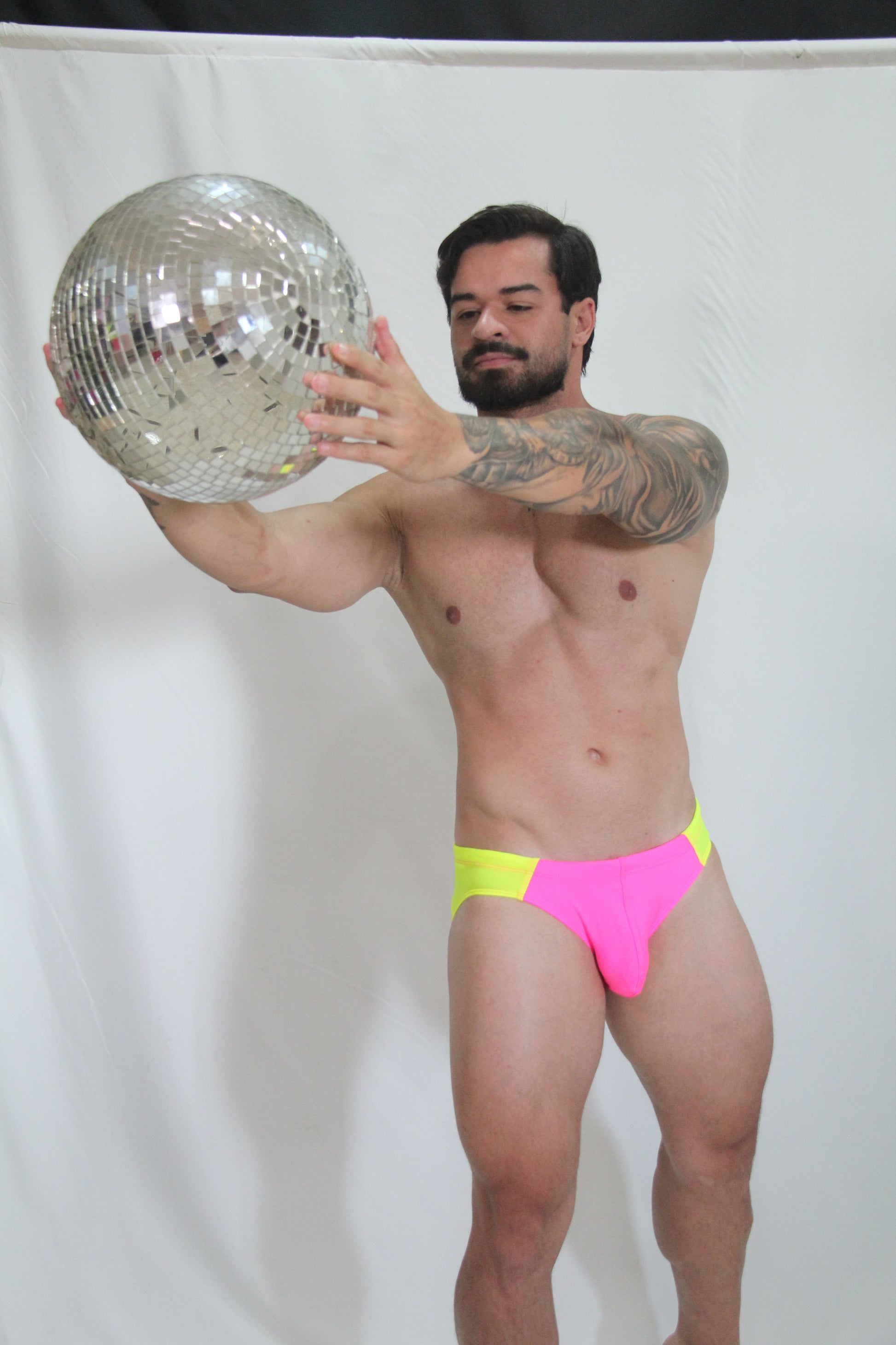 Shiny silver disco ball with mirrored facets reflecting light in a neon curved swim brief product image