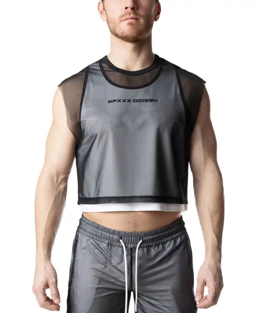 A person wearing a sheer black mesh crop top layered over a white tank top with dark text on the chest.