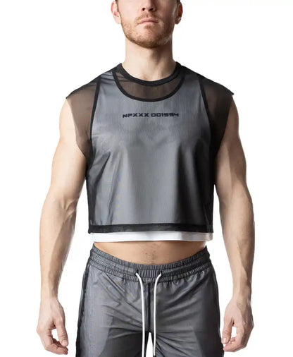 A person wearing a sheer black mesh crop top layered over a white tank top with dark text on the chest.