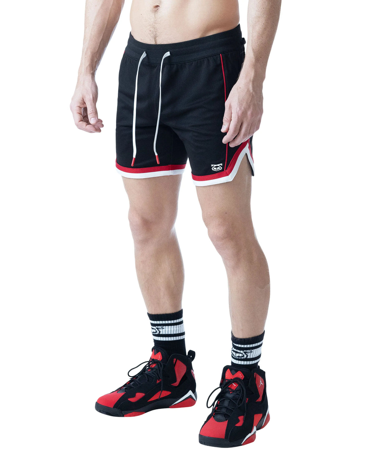 Black rugby shorts with red and white accents worn by a model with athletic shoes by Nasty Pig