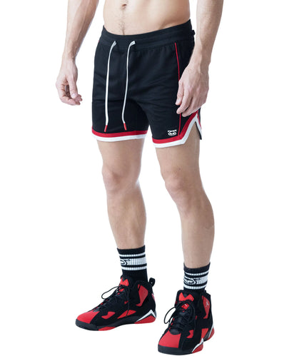Black rugby shorts with red and white accents worn by a model with athletic shoes by Nasty Pig