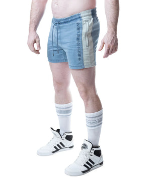 Light blue rugby shorts with elastic waistband, drawstring, and white side stripes featuring embossed text.