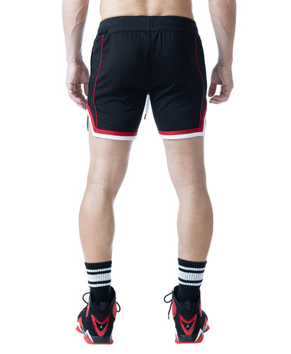 Black rugby shorts with red and white accents featuring a comfortable fit shown on a model from the back by Nasty Pig