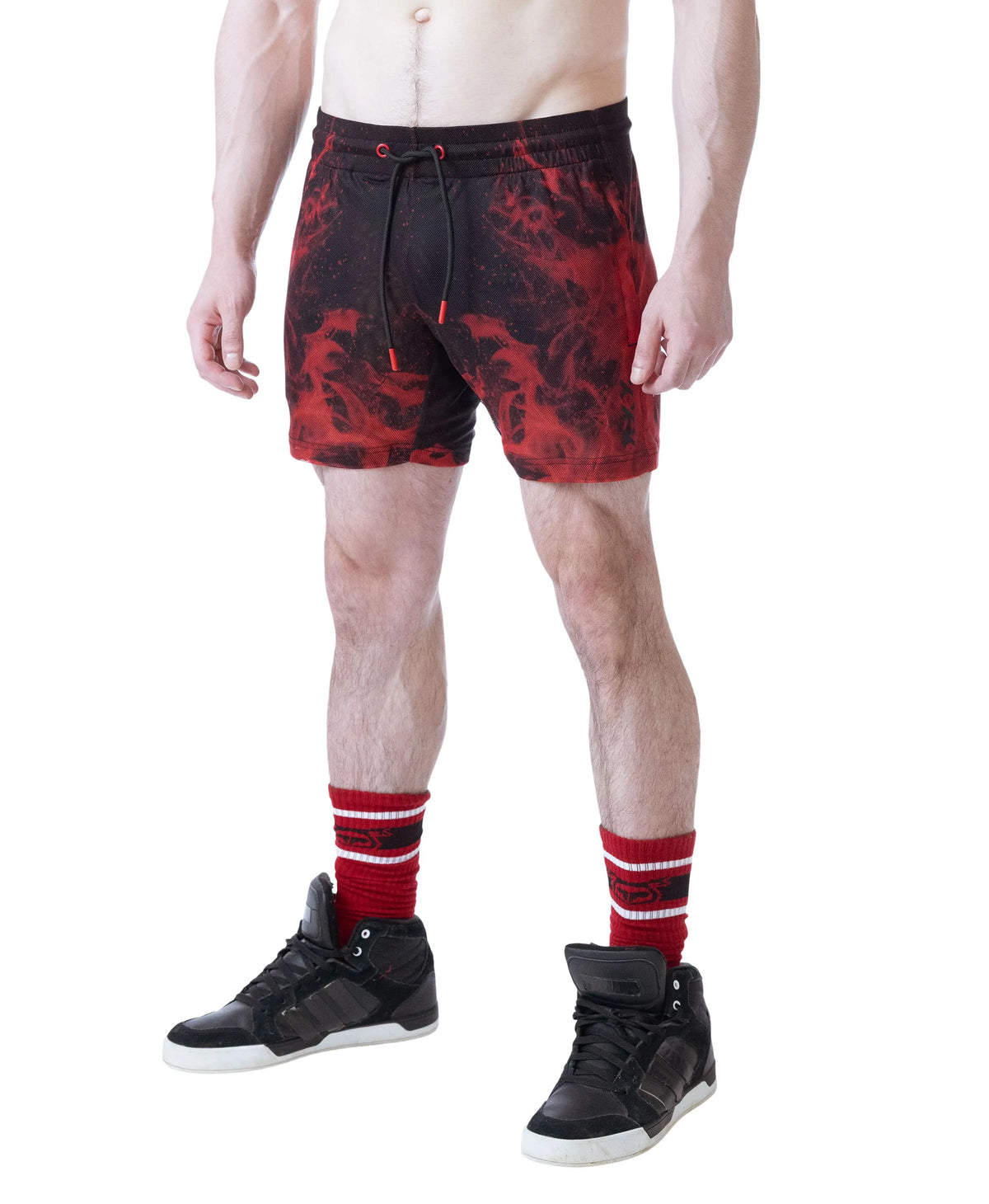 Red and black rugby shorts with a flame pattern worn by a model with black sneakers and red striped socks by Nasty Pig