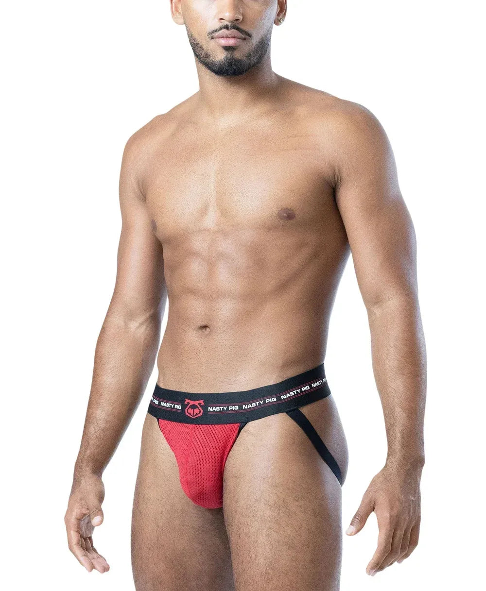 Red mesh jockstrap with black waistband featuring Nasty Pig logo worn by a model with a toned physique
