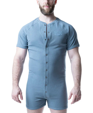 Dusty blue short-sleeve union suit with a button placket and chest logo, worn on a white background.