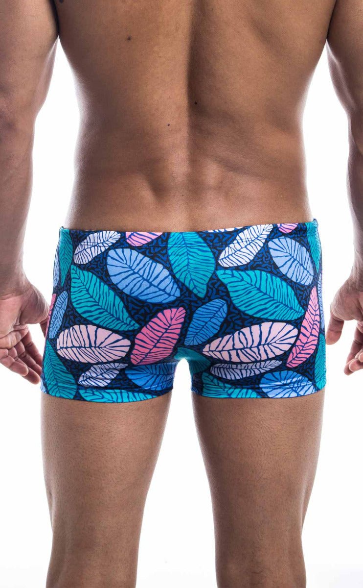 Oceanico square cut swim trunks with vibrant tropical leaf pattern in teal pink and white on dark blue base