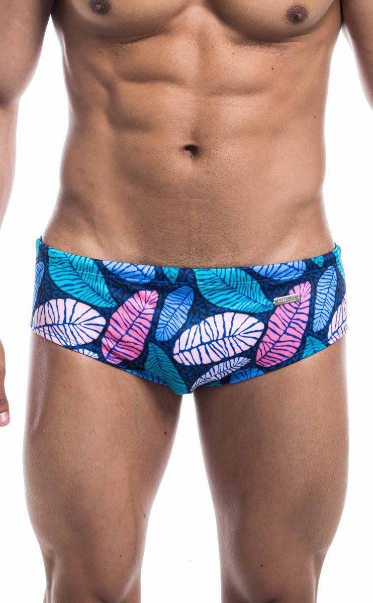 Oceanico swim brief featuring vibrant tropical leaf-patterned trunks in teal pink and white on dark blue base