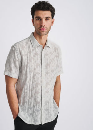 A powder-colored short-sleeve button-down shirt with a textured floral jacquard pattern.