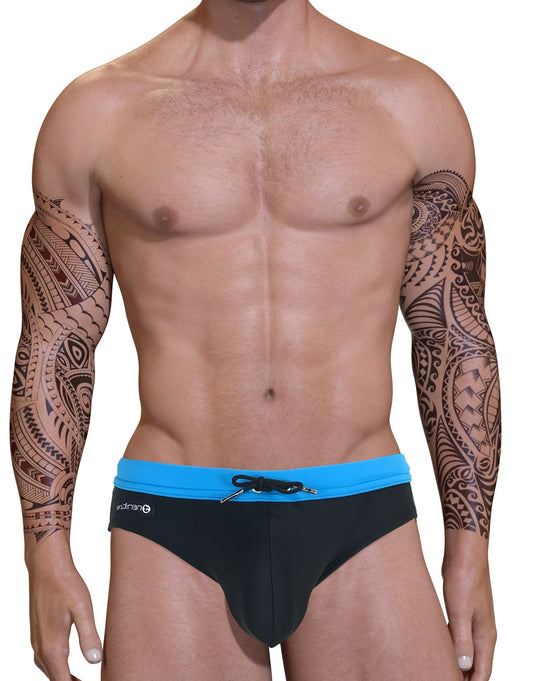Muscular man with tribal arm tattoos wearing a black swim bikini with a blue waistband and front drawstring.