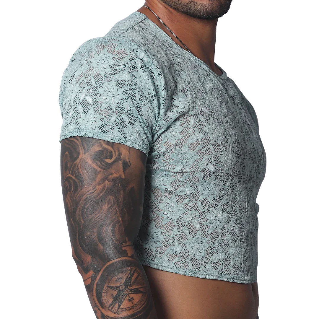 Sheer aqua blue floral lace crop top with short sleeves and a crew neck, worn by a man with arm tattoos.