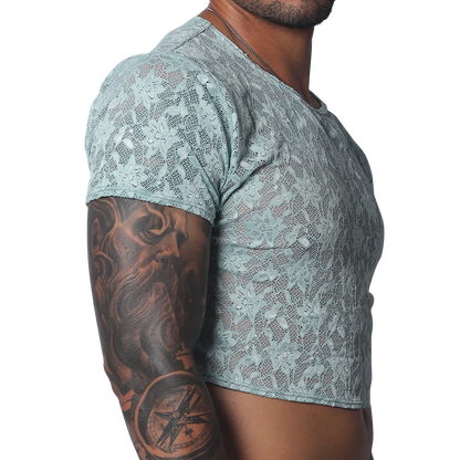 Sheer aqua blue floral lace crop top with short sleeves and a crew neck, worn by a man with arm tattoos.