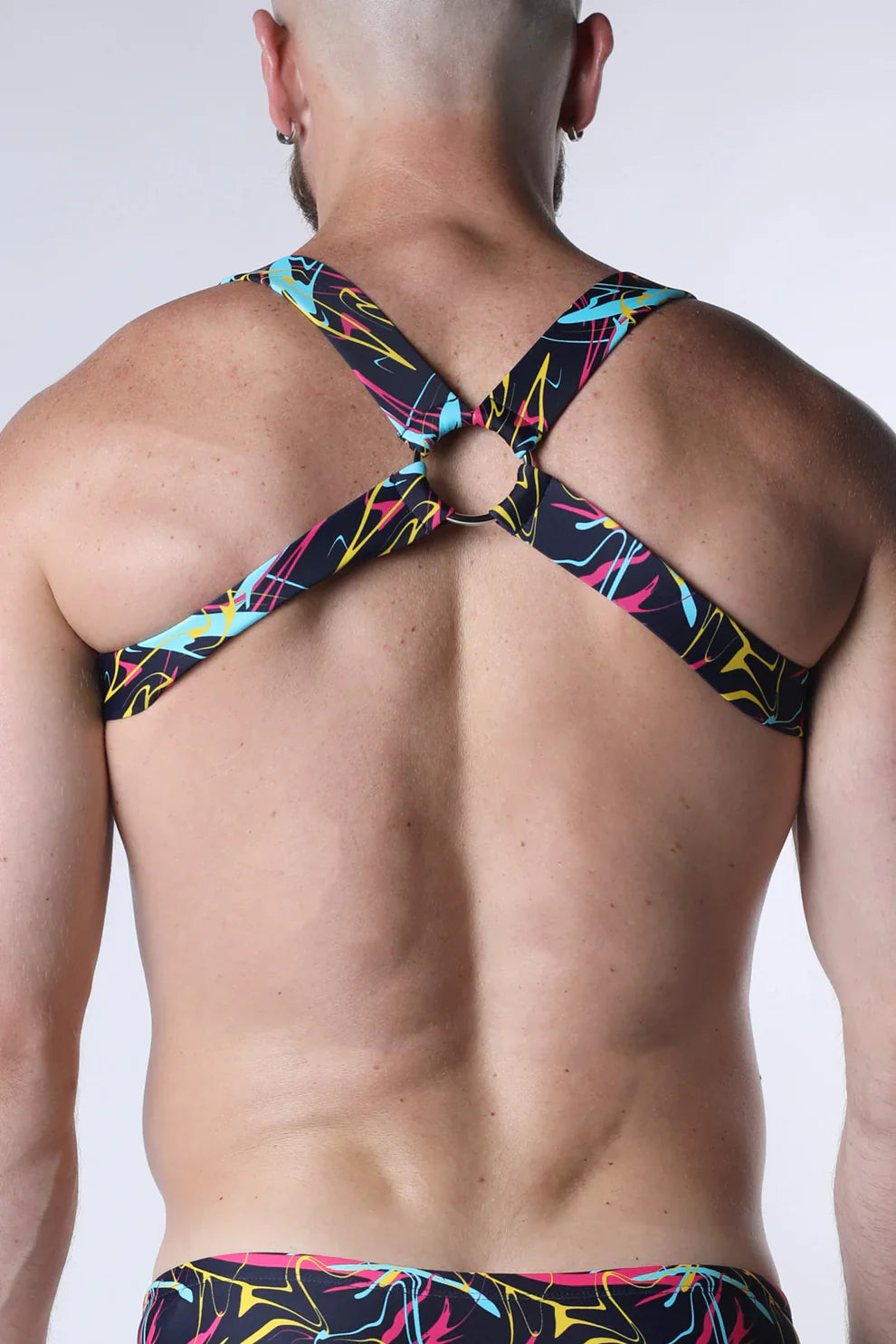 Black neon-colored abstract patterned strappy backless top with central metal ring shown from the back pulse elastic harness