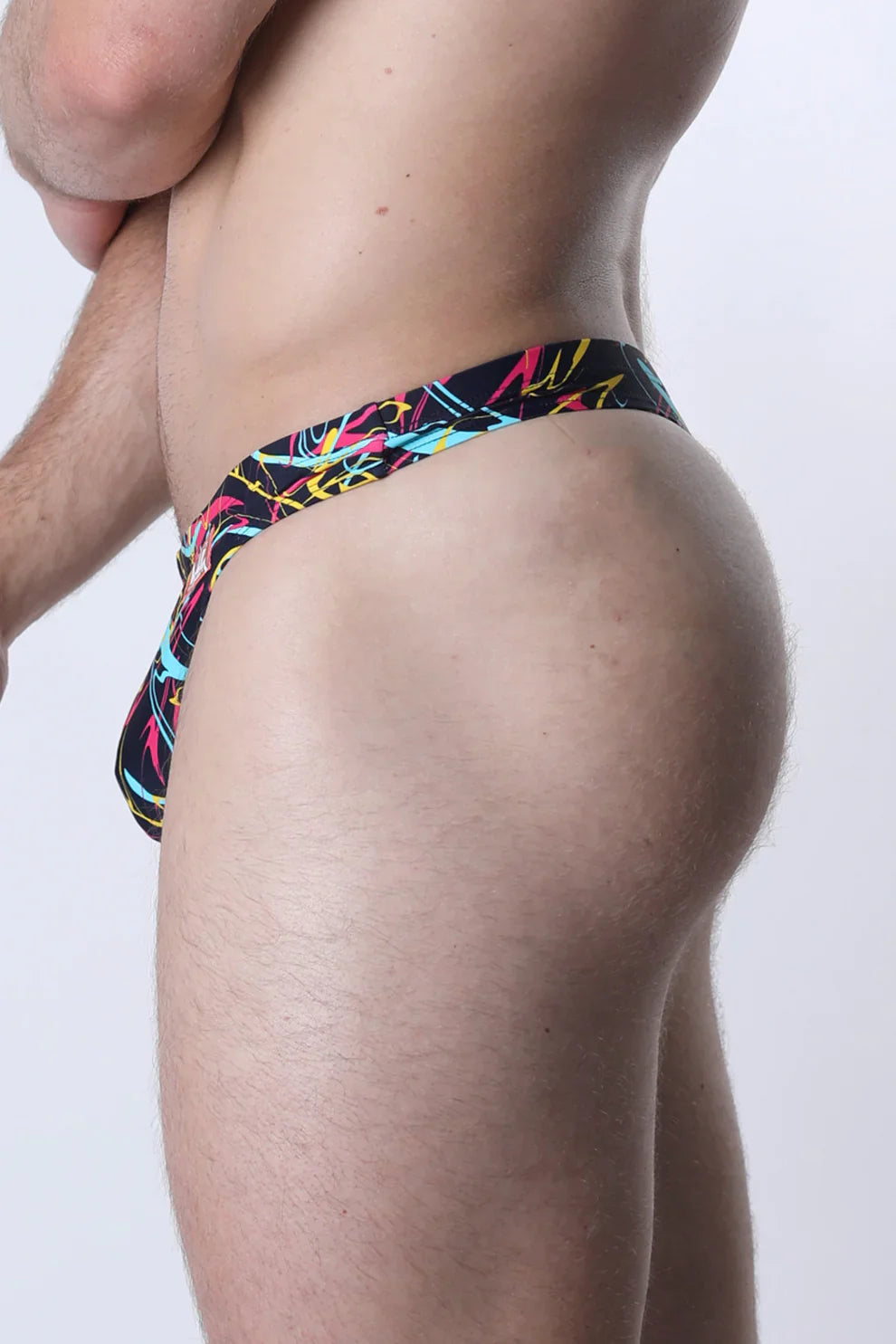 Pulse swim thong black briefs with vibrant graffiti pattern and neon pink yellow cyan accents front view