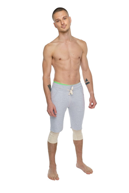 Light gray athletic shorts with neon green waistband and white drawstring paired with sand beige 3/4 performance yoga leggings