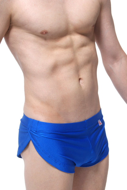 Bright blue PetitQ running shorts with sleek form-fitting swim trunk design and subtle brand tag on waistband