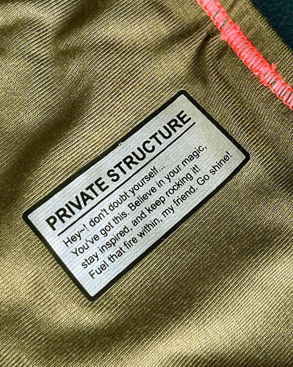 Olive green textured fabric bikini brief with black-bordered silver private structure label and inspirational message