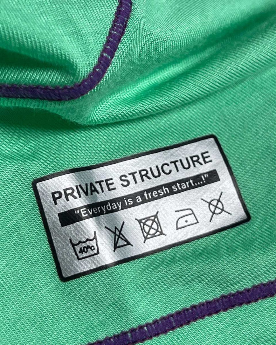 Green fabric with purple stitching and a silver private structure label showing care instructions on epus4570 hipster