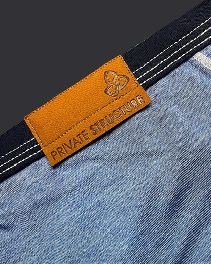 Orange leather brand tag with embossed logo and private structure text on denim fabric of low rise mini brief