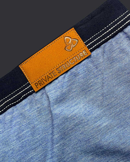 Orange leather brand tag with embossed logo and private structure text on dark blue denim waistband of barn boy low rise trunk