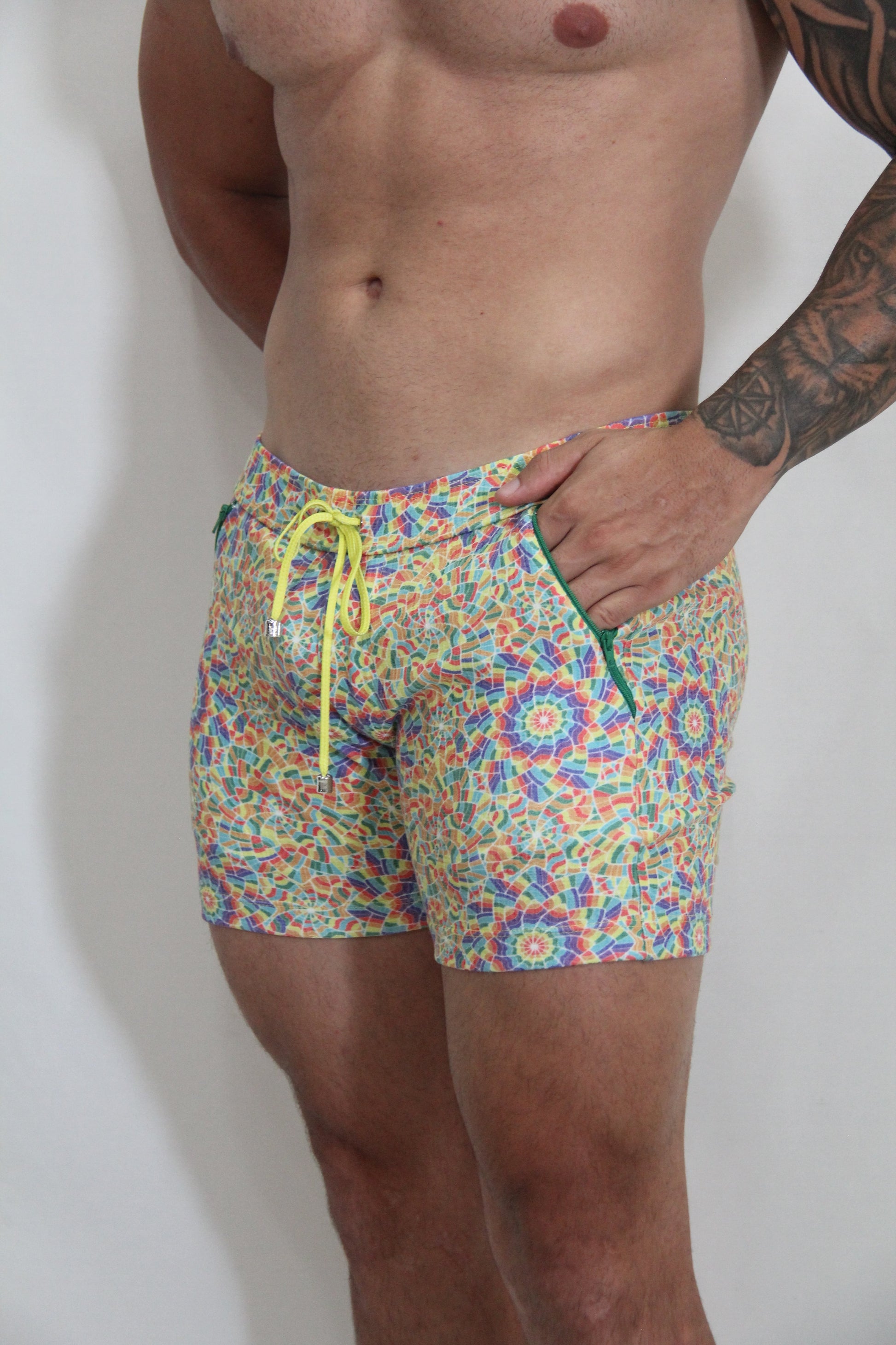 Rainbow kaleidoscope linen texture shorts featuring vibrant multicolored geometric swim trunks with neon yellow drawstring and green zipper accents