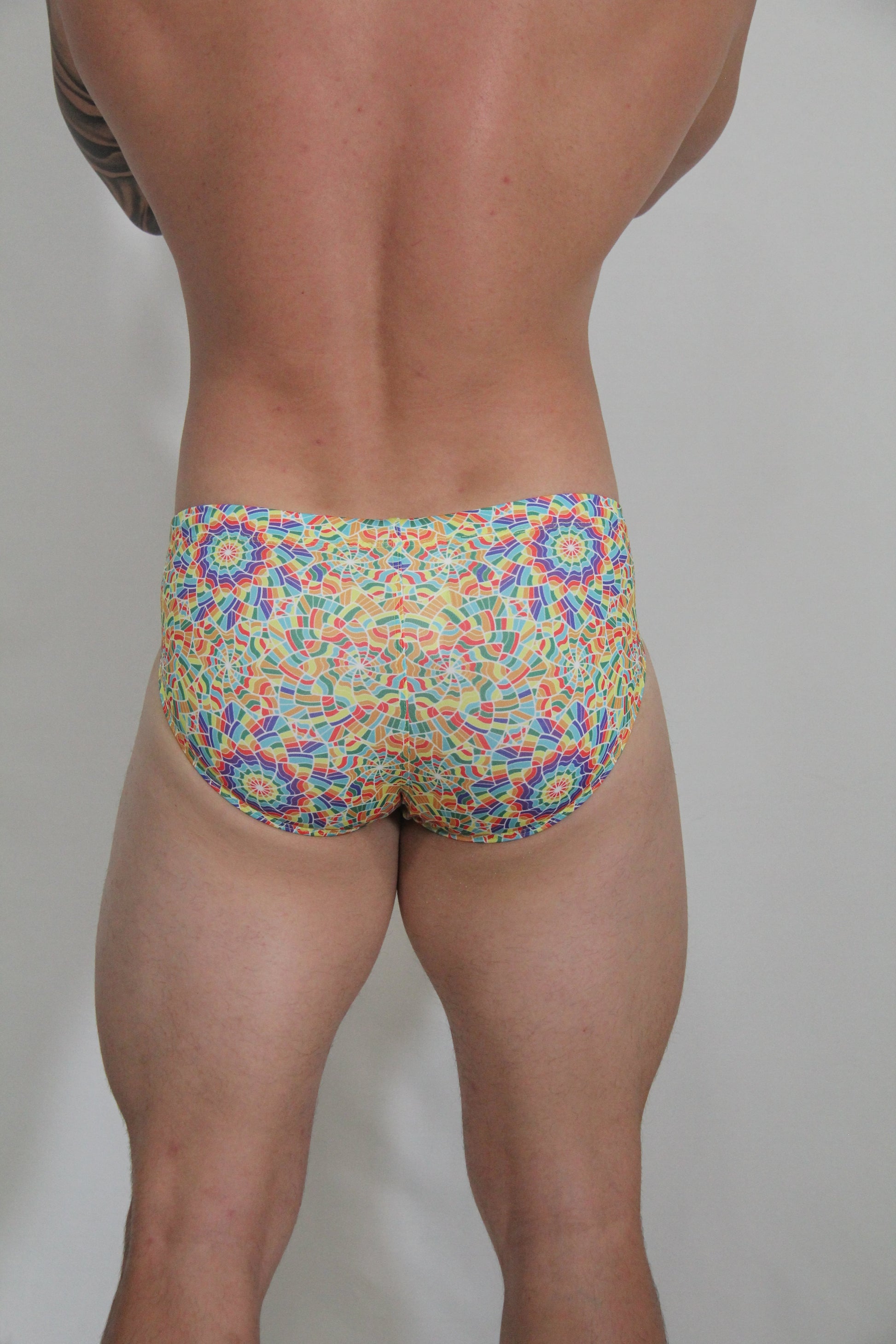 Rainbow kaleidoscope swim brief with vibrant multicolored mosaic geometric pattern for bold beachwear