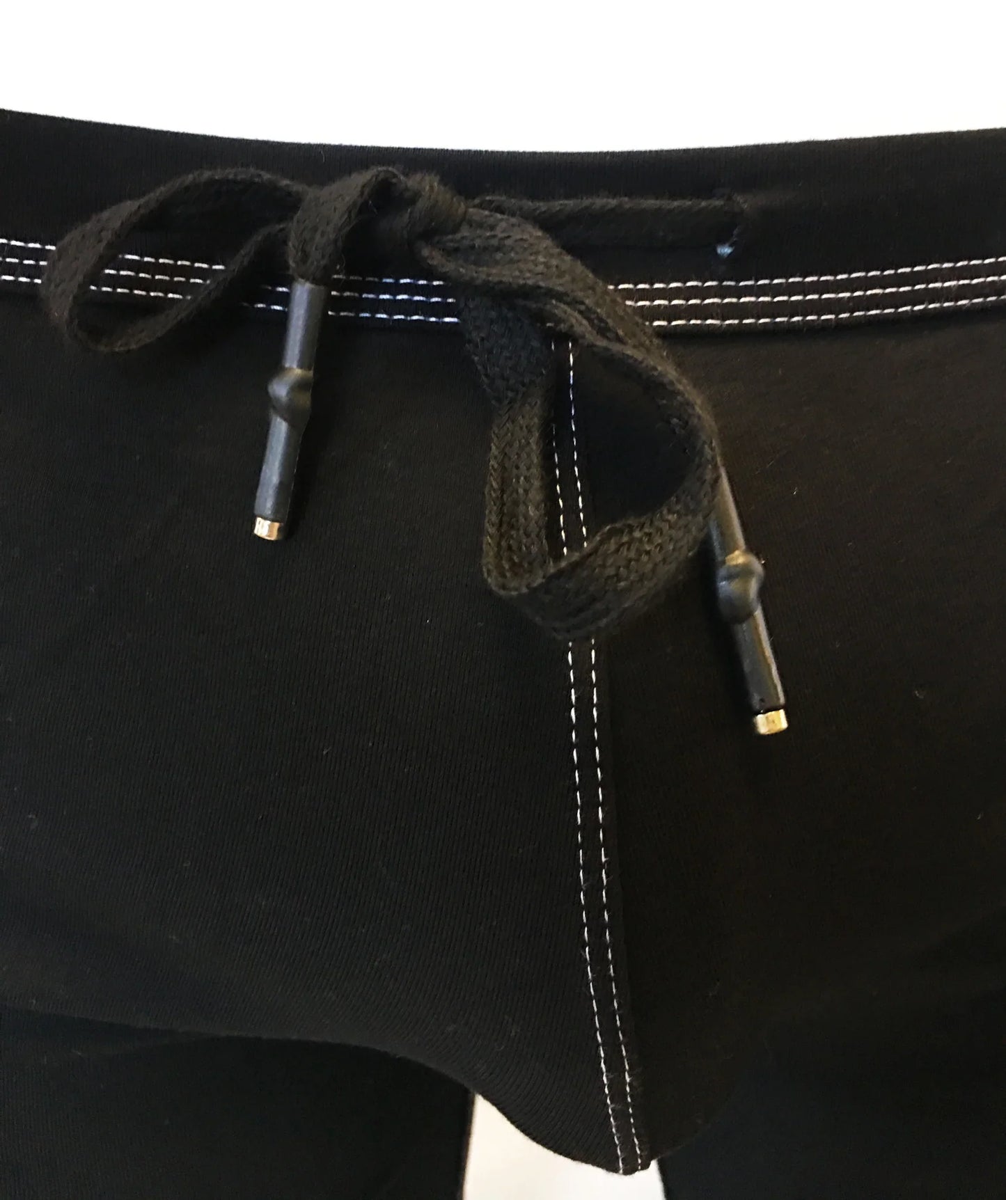 Black drawstring waistband with white stitching and metallic aglets on rainbow ribbon shorts