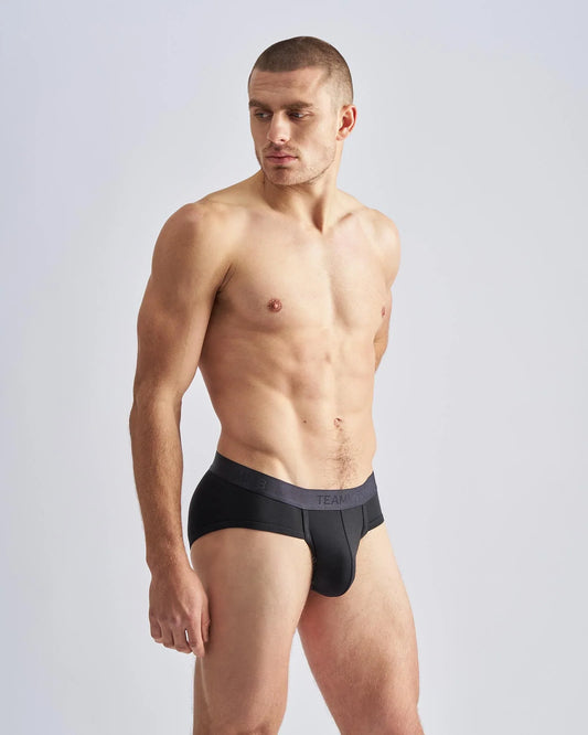 Black men’s REIGN briefs with a dark gray waistband featuring team branding in white lettering for everyday comfort
