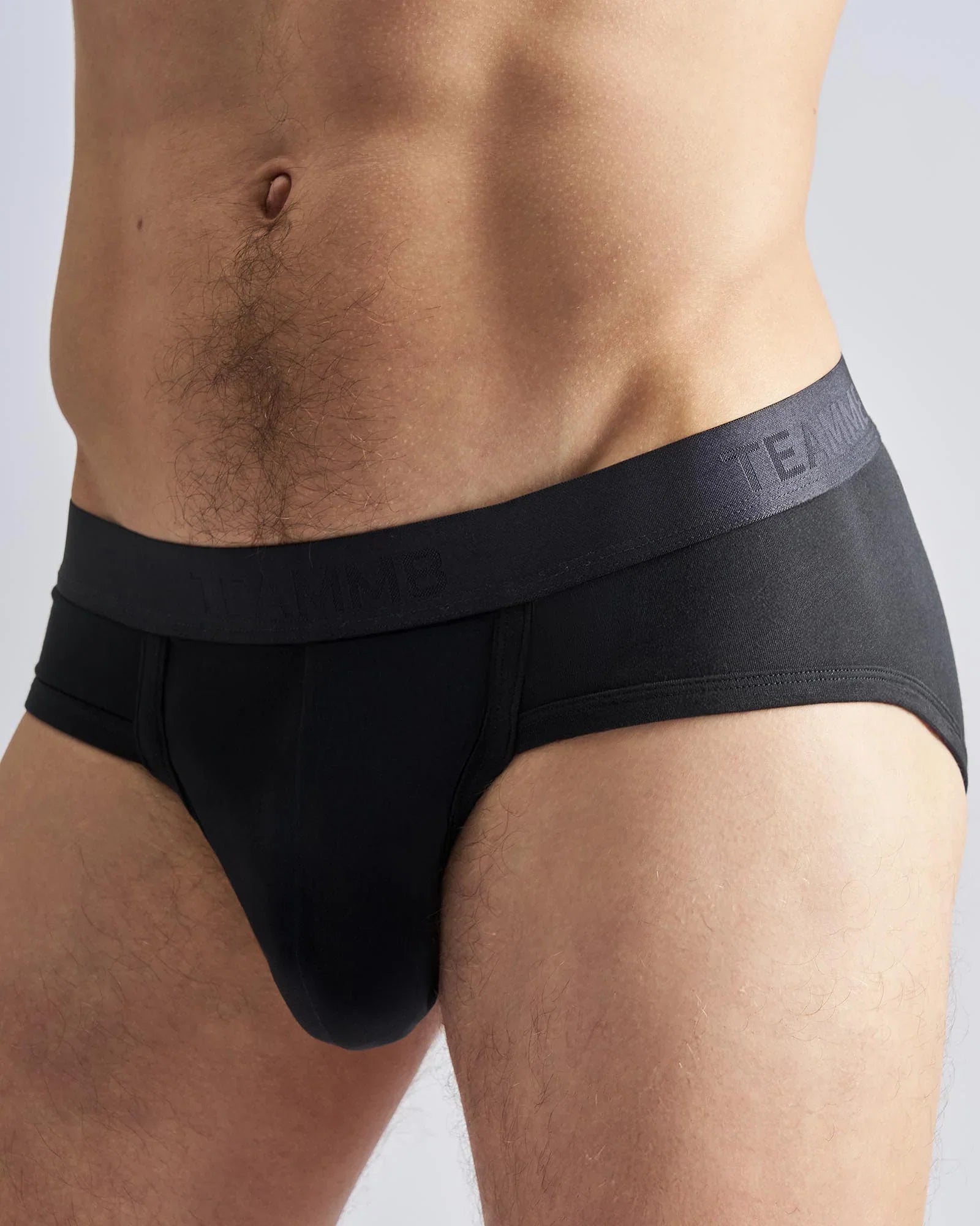 Black men’s briefs with a dark gray elastic waistband featuring the subtle team logo in the reign brief design