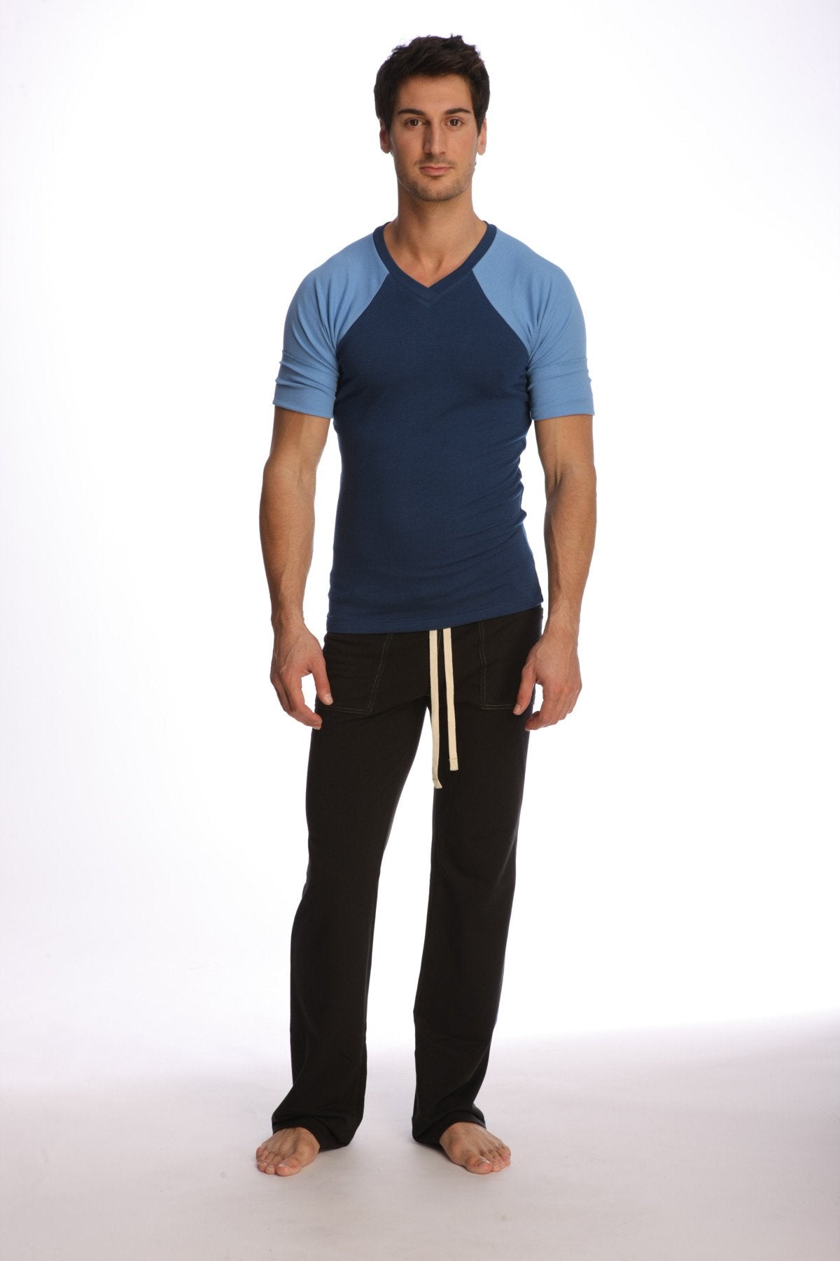 Man wearing a raglan virtual crew neck t-shirt in royal blue with navy and light blue sleeves and black pants with cream drawstrings