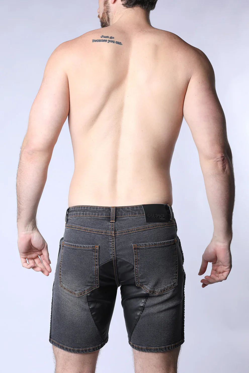 Dark gray denim shorts with a black leather Saddleback denim short brand patch on the waistband back side view