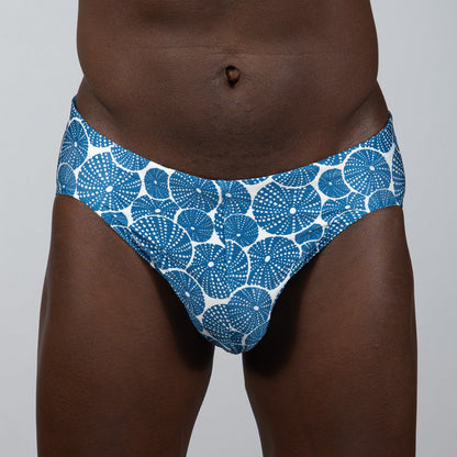 Blue and white patterned sand dollar brief swim trunks featuring a repeating circular dotted motif design