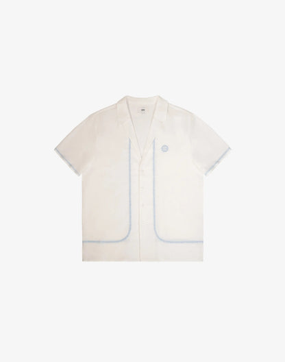 Santorini linen shirt is a crisp white short-sleeved button-up with subtle light blue piping on pockets and seams