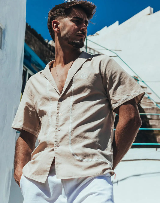 Beige santorini linen shirt with short sleeves and embroidered detailing along the placket and hem