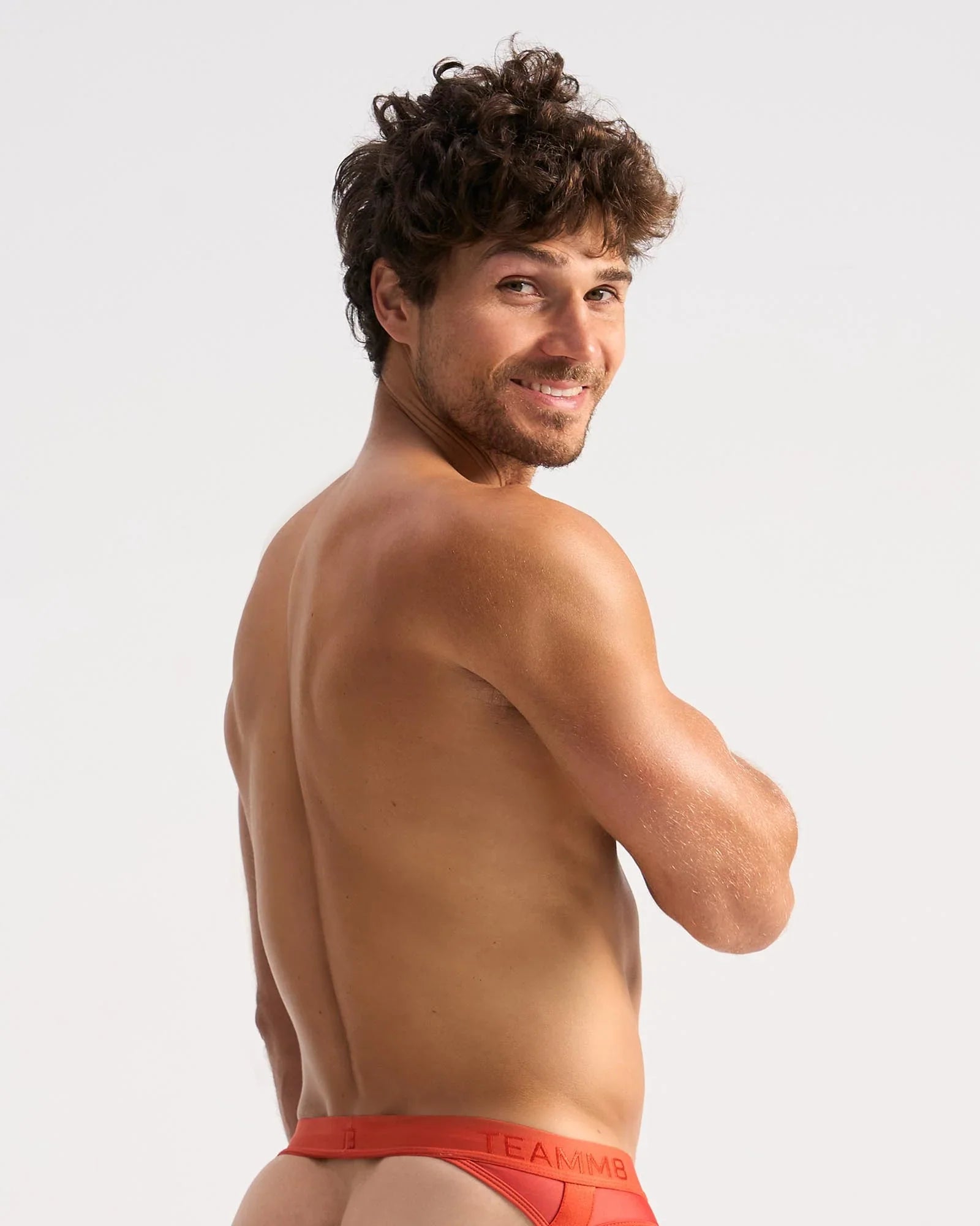 A man wearing bright red calvin klein score sheer jock briefs with a visible logo waistband in front view