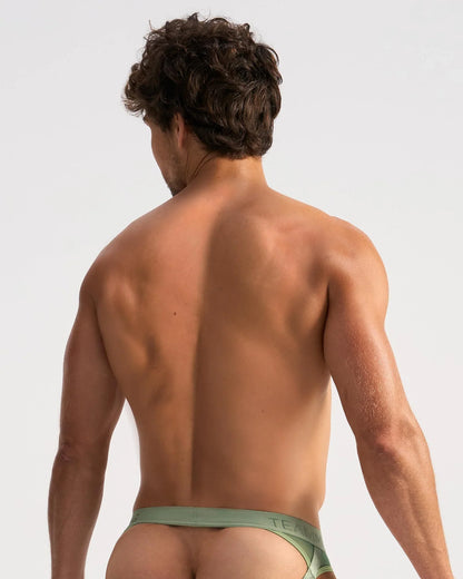 A man wearing olive green low-rise sheer jock briefs with the brand teal on the waistband in the front view