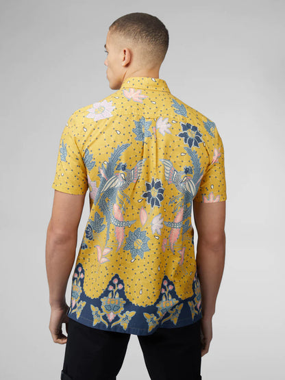A vibrant yellow short-sleeved shirt with blue and pink floral bird patterns and a navy blue hemband from signature abstract botanical print