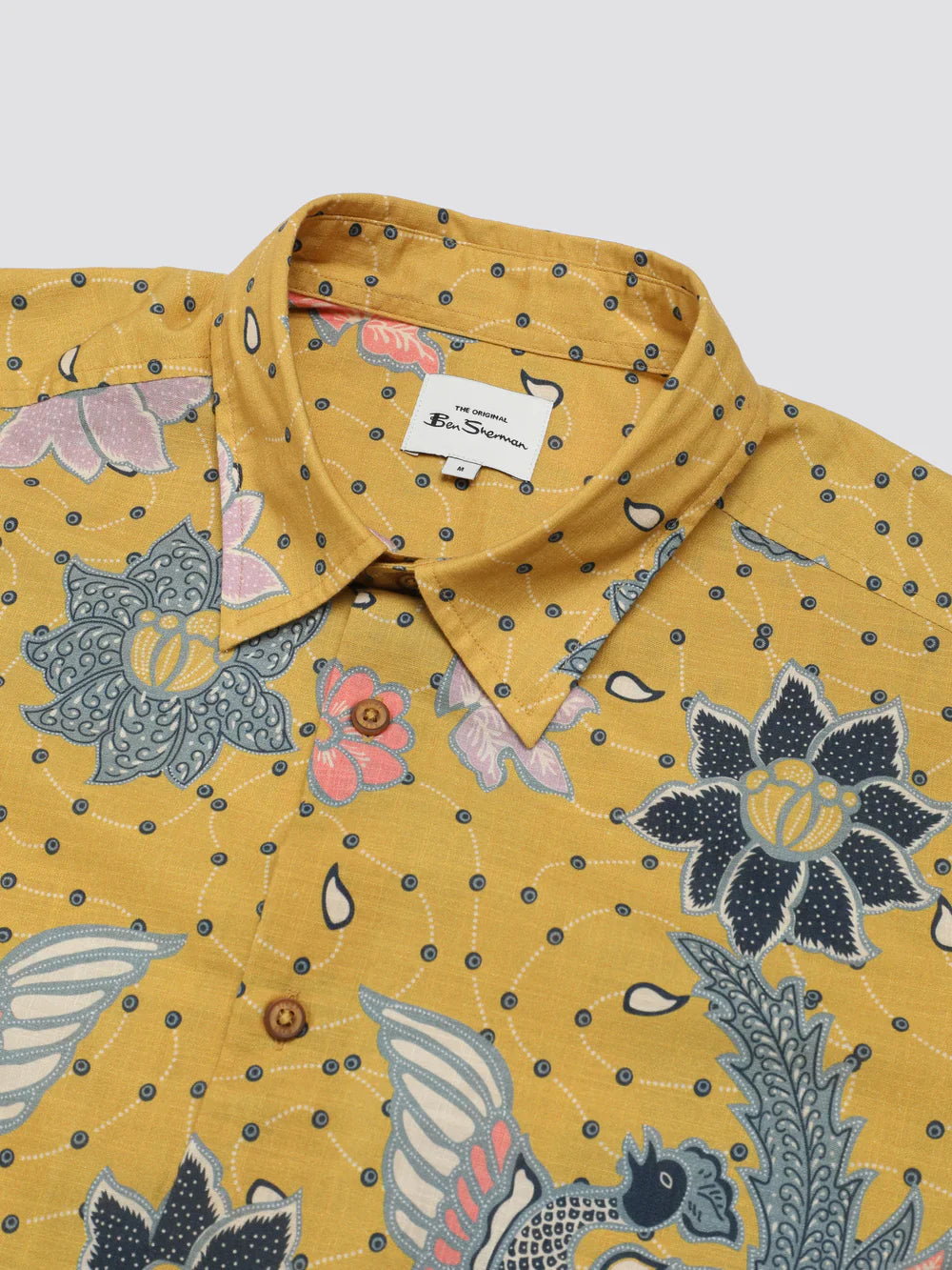Yellow button-up shirt with signature abstract botanical print featuring vibrant pink blue and gray floral and bird patterns