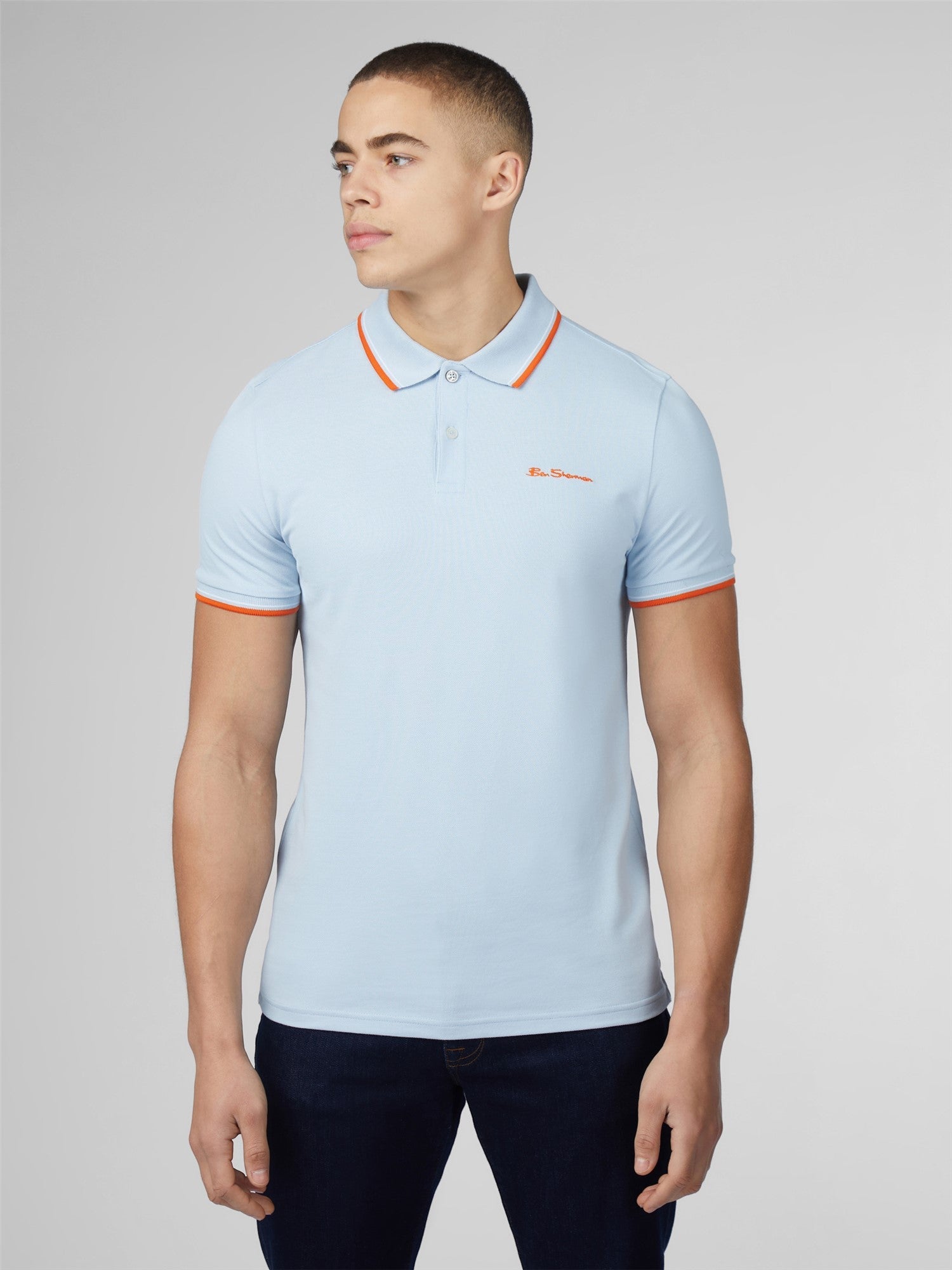 Light blue signature polo shirt with orange collar and sleeve trim featuring a small embroidered chest logo