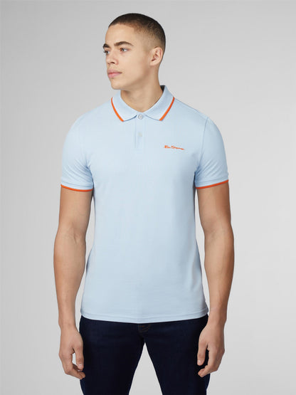 Light blue signature polo shirt with orange collar and sleeve trim featuring a small embroidered chest logo