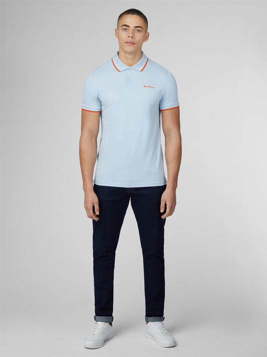 Light blue signature polo shirt with orange trim on collar and cuffs featuring small embroidered chest logo