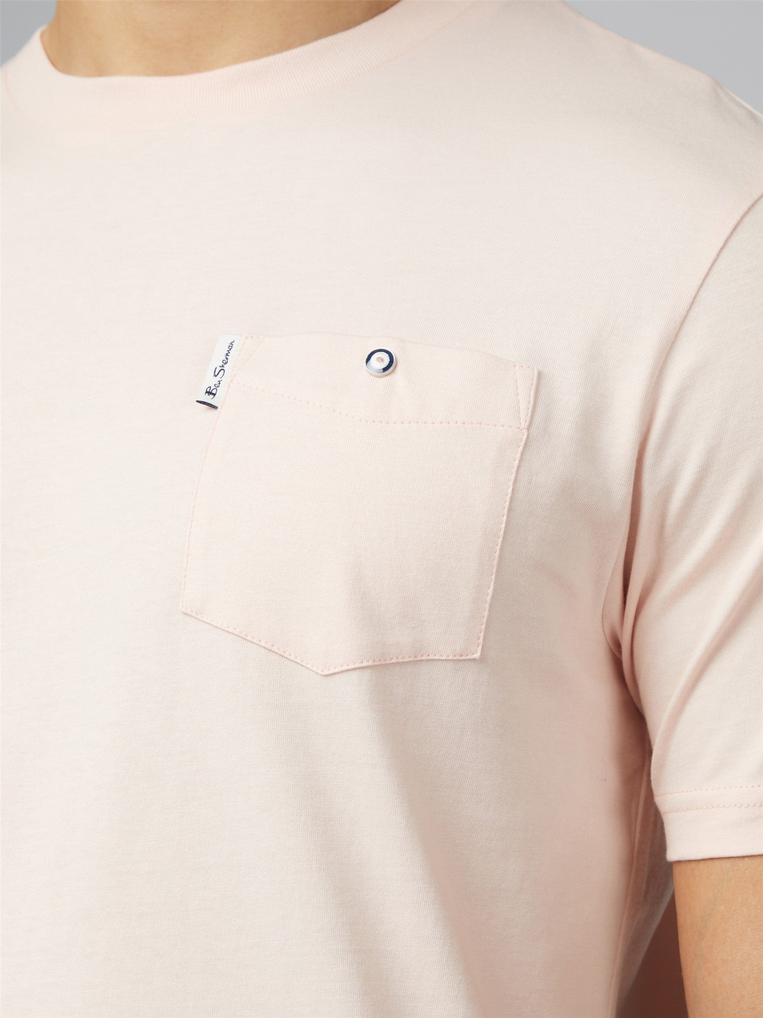 A soft blush pink signature t shirt with short sleeves chest pocket silver button and small branded tag