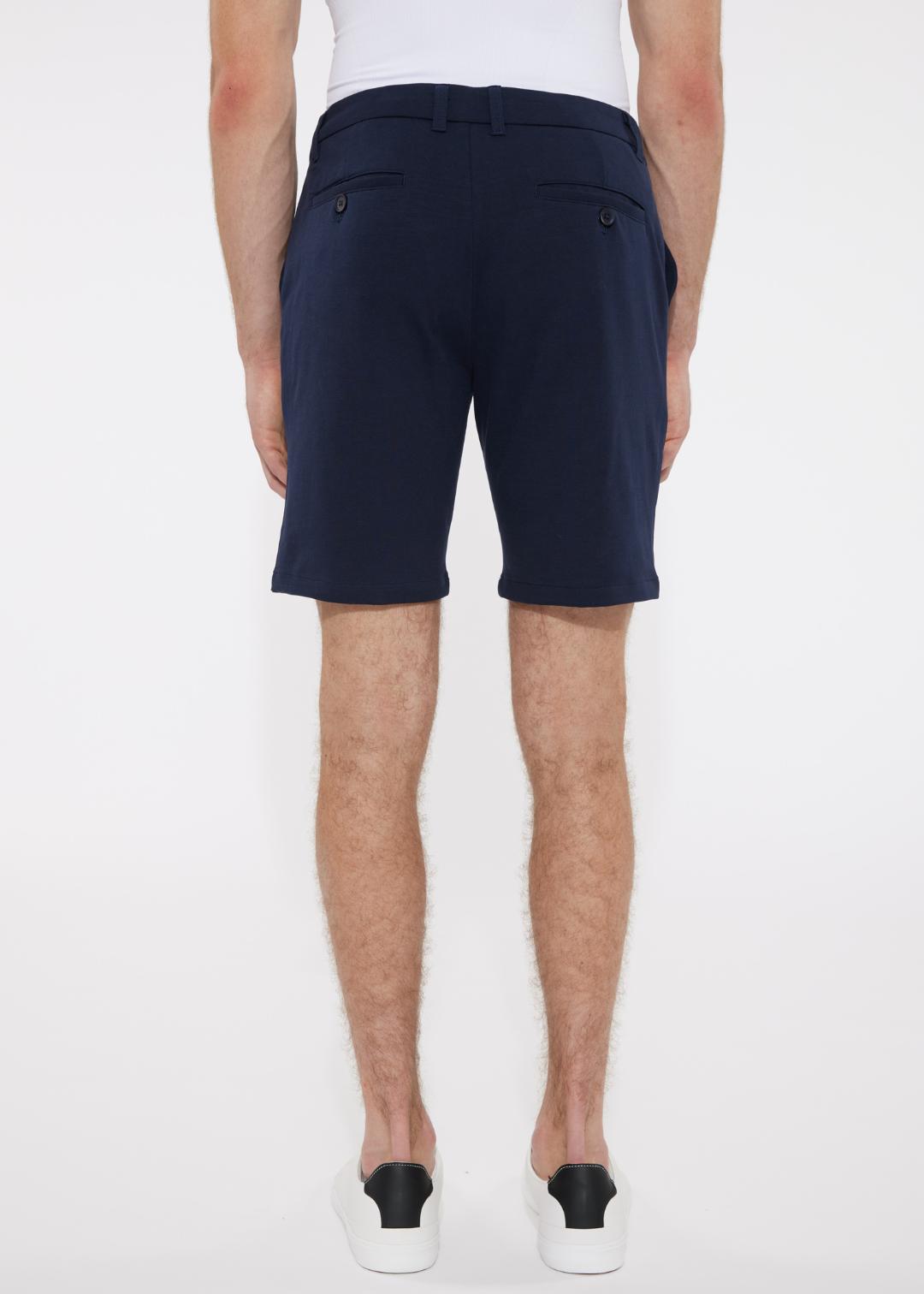 Navy blue solid stretch knit shorts with tailored sleek cut and buttoned back pockets shown from the back side