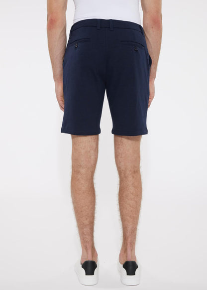 Navy blue solid stretch knit shorts with tailored sleek cut and buttoned back pockets shown from the back side