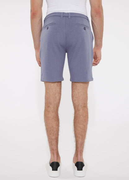 A pair of men’s solid stretch knit shorts in soft lavender with smooth lightweight fabric and dark button accents on back pockets