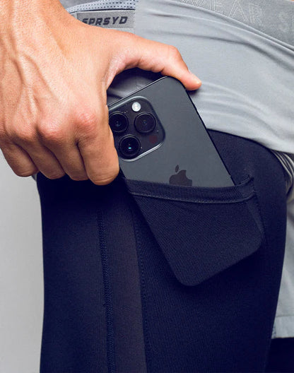Black iphone with triple-camera system in the back pocket of dark navy spr flex short athletic leggings