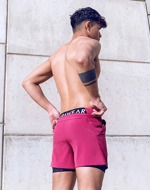 The spr max short features vibrant fuchsia athletic shorts with a black waistband layered over dark blue compression shorts