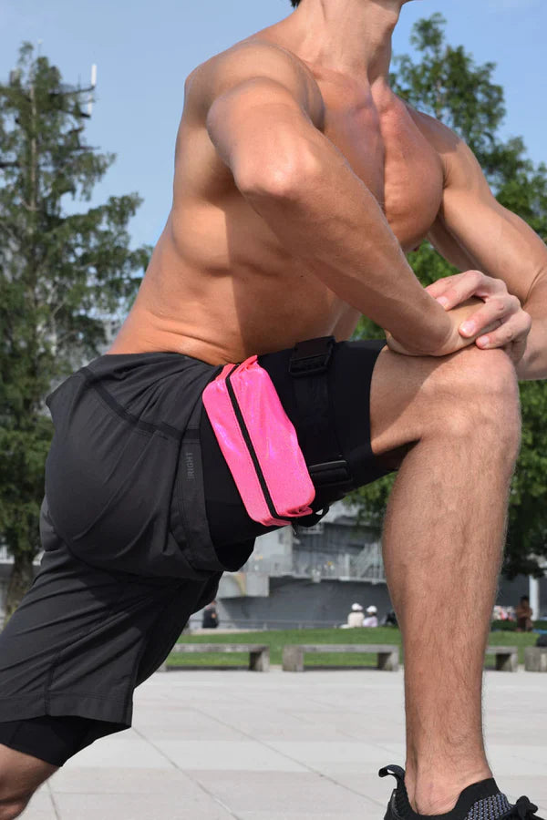 Bright pink ssbag running belt with black trim worn by man in athletic shorts for hands-free running storage