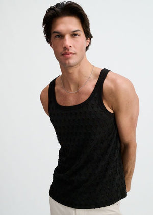 A person wearing a black, stretch-ripped knit tank top with a scoop neckline against a light background.